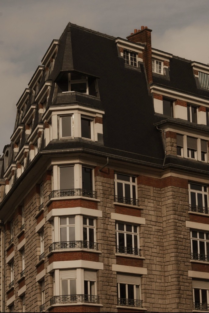 French corner building with stone, brick accents and mansard roof