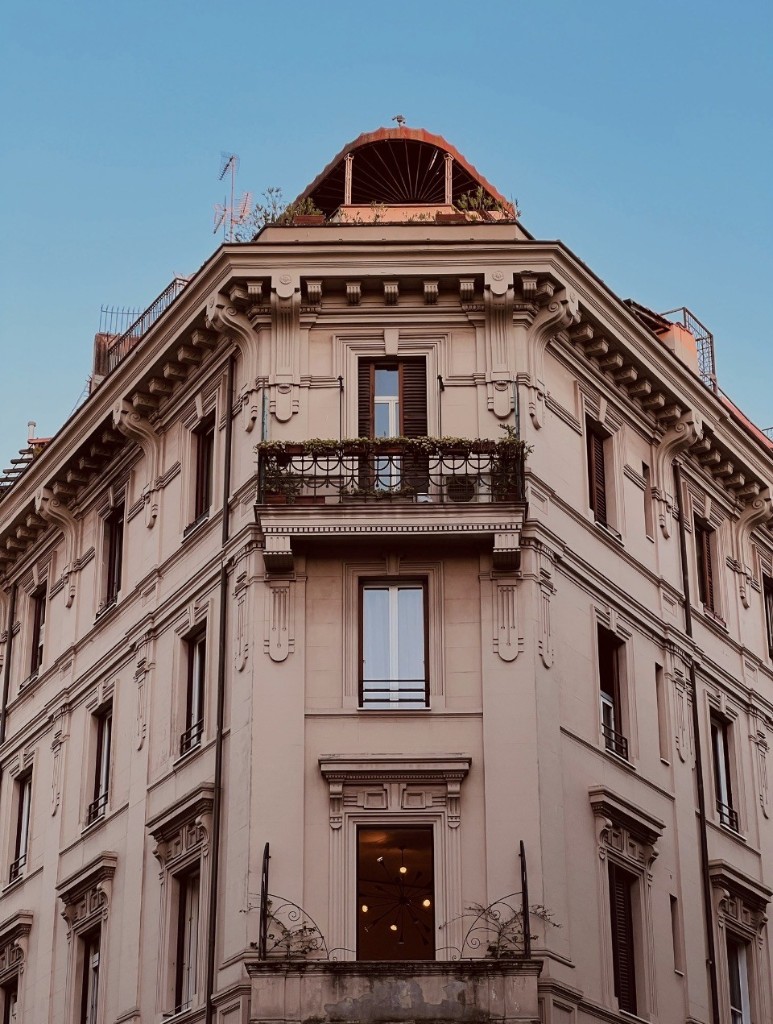 Italian corner building with wrought-iron balconies and cornice